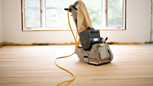Eurohardwood Flooring image of a sander refinishing the flooring of a home.